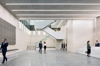 reception, a big artwork hanging on the left hand side with a modern staircase ahead, people walking through the space