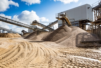 sunny view of the mining conveyor belts surrounded by piles of sand