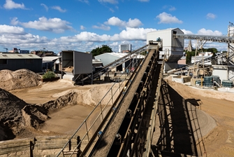 view onto a mine, in the forefront you have a long conveyor belt carrying gravel