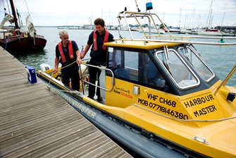 Two men getting out of a yellow boat with text harbour master on it