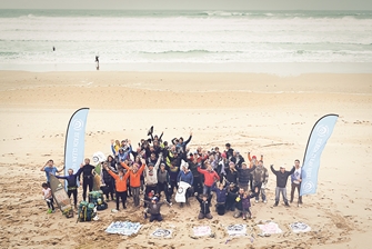 a large group of people cheerfully posing for a photo next to 'beach clean' banners