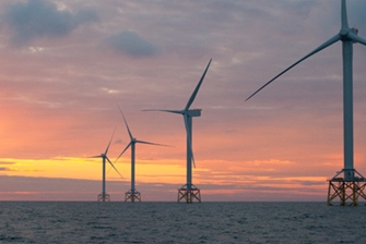 Image of wind turbines against a setting sun in the sky